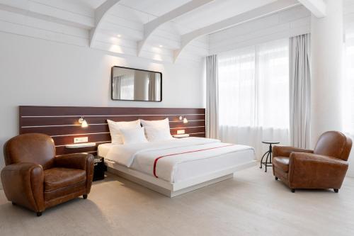 a hotel room with a bed and two chairs at Ruby Lotti Hotel Hamburg in Hamburg