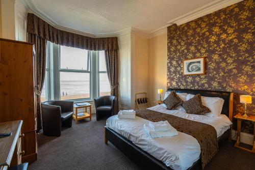 um quarto de hotel com uma cama e uma grande janela em Can-Y-Bae Hotel em Llandudno