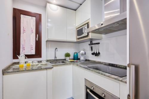 una cocina con armarios blancos y fregadero en Apartment Near Picasso Museum, en Málaga