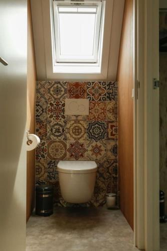a bathroom with a toilet and a window at Vrijvakantiehuis Duinweg 2b in Oostkapelle