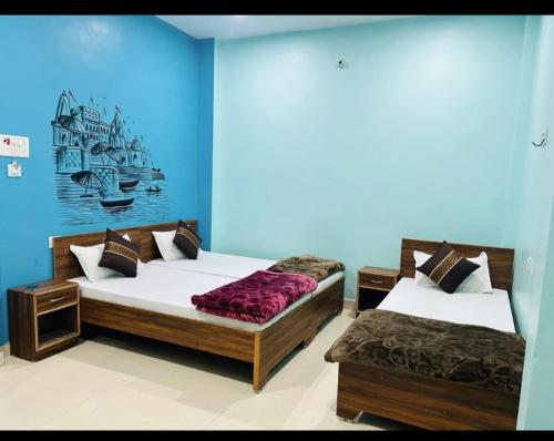 Duas camas num quarto com paredes azuis em Lotus Paying Guest house em Varanasi