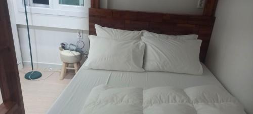 uma cama com almofadas brancas num quarto em Hamdeok Pool Villa Ferrari em Jeju