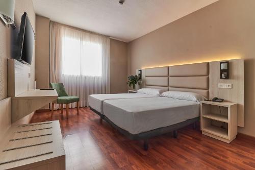 Un dormitorio con una gran cama blanca y una ventana en Hotel Zaragoza Royal, en Zaragoza