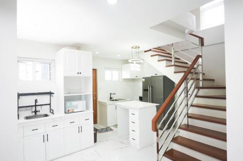 a kitchen with white cabinets and a staircase at Luxurious Place Mountain View Spacious with WIFI Near SM Lucena in Lucena