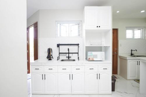 a white kitchen with white cabinets and a sink at Luxurious Place Mountain View Spacious with WIFI Near SM Lucena in Lucena