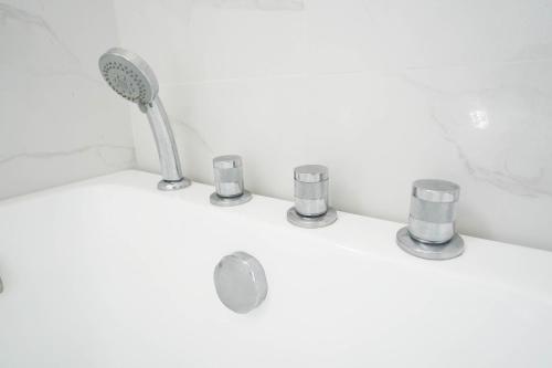 a bathroom sink with a shower head and cups at Luxurious Place Mountain View Spacious with WIFI Near SM Lucena in Lucena