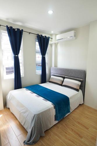 a bedroom with a large bed with blue curtains at Luxurious Place Mountain View Spacious with WIFI Near SM Lucena in Lucena