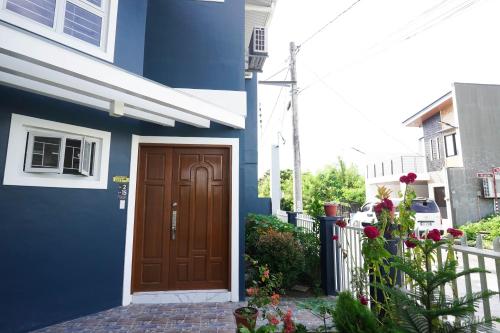 a blue house with a brown door and a fence at Luxurious Place Mountain View Spacious with WIFI Near SM Lucena in Lucena