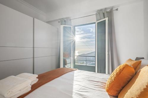 a bedroom with a bed and a large window at Il Tramonto by Homie in Ribeira Brava