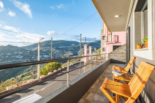 two wooden chairs on a balcony with a view at Il Tramonto by Homie in Ribeira Brava
