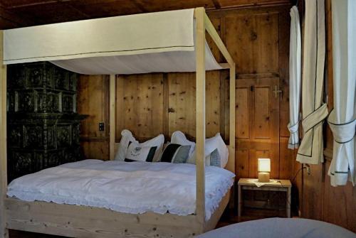 1 dormitorio con cama con dosel y pared de madera en Widum Obernberg Nikolaus Bergsuite, en Obernberg am Brenner