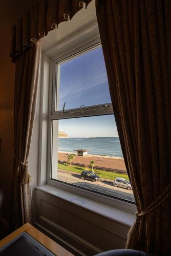 a window with a view of the beach at Can-Y-Bae Hotel in Llandudno