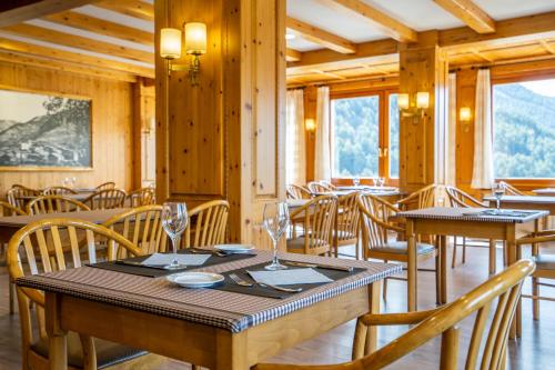 uma sala de jantar com mesas, cadeiras e janelas em Abba Ordino Babot Hotel em Ordino