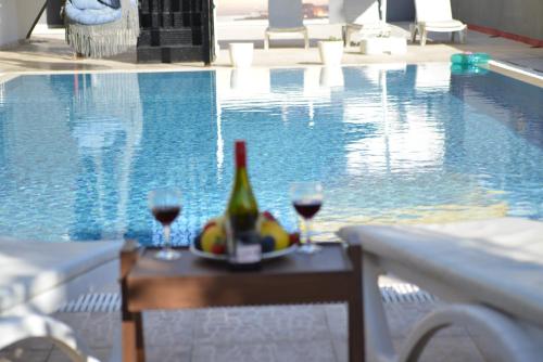 a table with glasses of wine and fruit next to a swimming pool at La Rezidans Hotel in Antalya