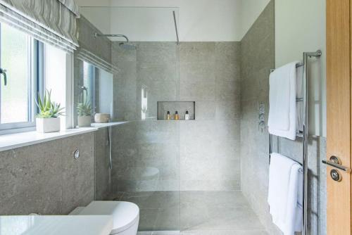 a bathroom with a shower and a toilet and a sink at The Old Cherry Barn - Luxury barn conversion in Faversham