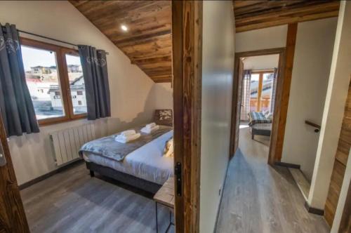 een slaapkamer met een bed en een groot raam bij Chalet 2 sur la route du tour in Huez