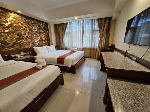a hotel room with two beds and a flat screen tv at Ritz Boutique Hotel in Pattaya South