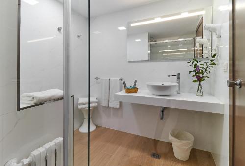 Baño blanco con lavabo y espejo en Hotel Zaragoza Royal, en Zaragoza