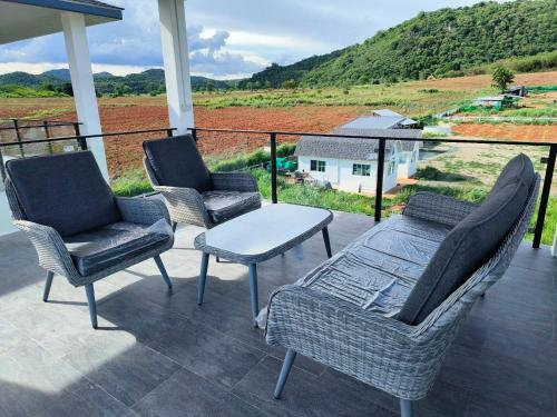 três cadeiras e uma mesa num alpendre com vista em Miramonti Pool Villa เขาใหญ่ em Wangkata