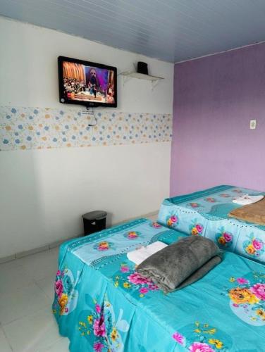 um quarto com uma cama com um cobertor azul e uma televisão em Hostel das Flores em Belém