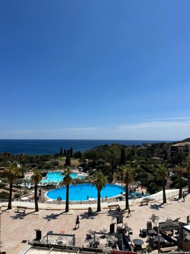 uma vista para uma piscina com palmeiras e para o oceano em cap esterel em Agay - Saint-Raphaël