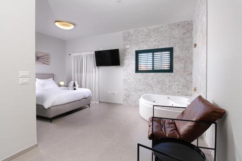 a bedroom with a bed and a tub and a television at 49 Boutique in Zikhron Ya‘aqov