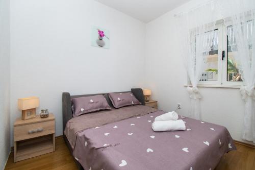 - une chambre avec un lit doté de draps violets et une fenêtre dans l'établissement Apartments Tiho, à Vodice