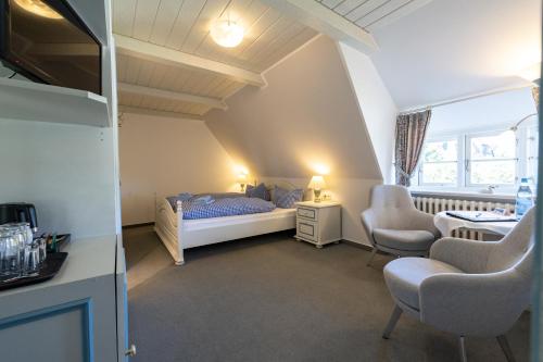 a bedroom with a bed and two chairs and a table at Haus Amanda in Norddorf