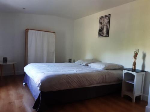 a bedroom with a large bed with a night stand at Maison de campagne 10 personnes. in Brizambourg