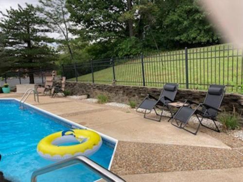 una piscina con sillas y un inflable amarillo en AirBnB Florissant, fire pit - pool open!, en Florissant