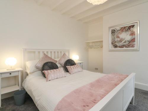a bedroom with a large white bed with pink pillows at Kitty Cottage in Blackpool