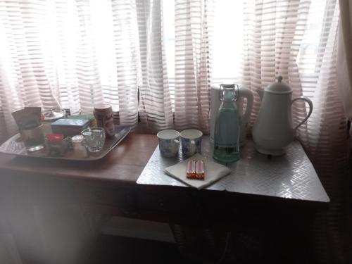 una mesa cubierta con tazas y una jarra y una bandeja con tazas en The Boat House BED ONLY NO BREAKFAST, en Aultbea