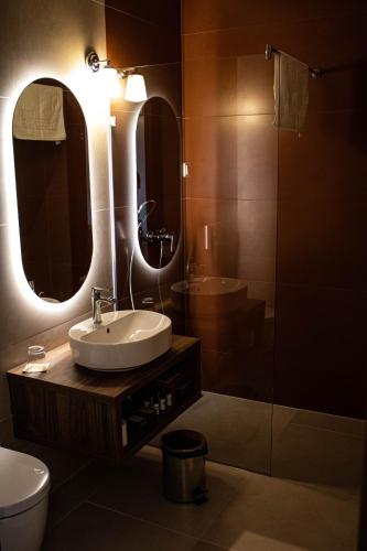 a bathroom with a sink and a toilet and two mirrors at Öreg Halász Fogadó in Tát