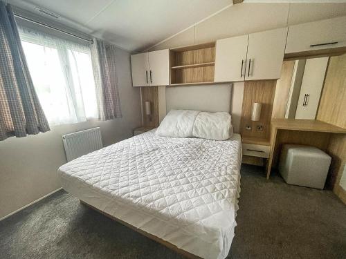 a bedroom with a bed and a desk and a window at Beautiful 6 Berth Caravan With Decking, Wifi And Field Views Ref 29029sv in Clacton-on-Sea