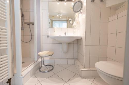 a white bathroom with a sink and a toilet at Haus Amanda in Norddorf