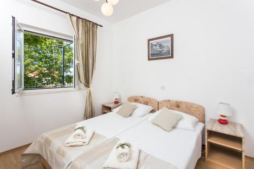 a white bedroom with two beds and a window at Apartments Olive in Mlini