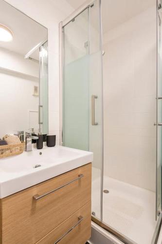 une salle de bain avec une douche, un lavabo et un miroir dans l'établissement Paris la Défense, lumineux et cosy, à Courbevoie