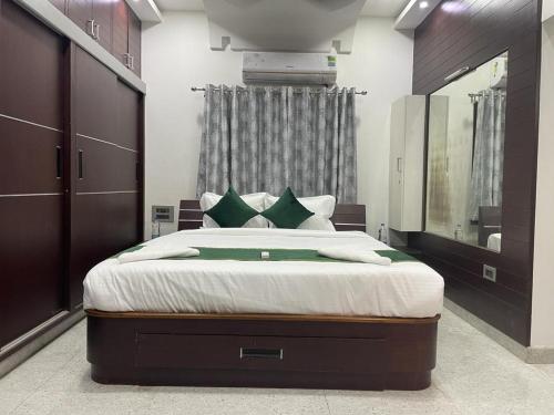 een slaapkamer met een groot bed met witte lakens en groene kussens bij Atithi Homestay in Tirupati
