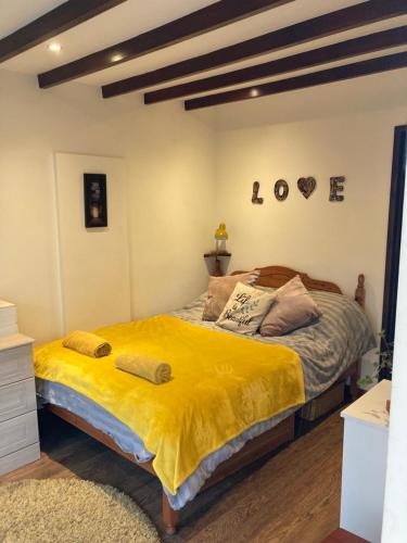 a bedroom with a large bed with a yellow blanket at Pilgrims Rest with Annexe in Cheddar