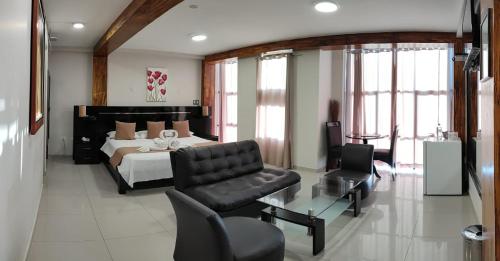 Aura Hotel في تشيكلايو: غرفة نوم بسرير واريكة وكرسي
