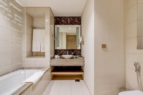 a bathroom with a sink and a tub and a mirror at GlobalStay DAMAC Towers by Paramount Business Bay Apartments in Dubai
