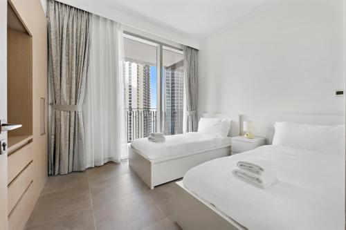 Dieses weiße Zimmer verfügt über 2 Betten und ein großes Fenster. in der Unterkunft WelHome - Stunning Apartment With Sea Views in Creek Harbour in Dubai