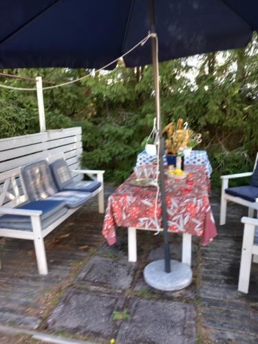 a table with an umbrella next to two chairs at Vaskio-bed in Salo