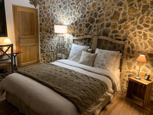 - une chambre avec un lit et un mur en pierre dans l'établissement Aux 3 Forêts, à Bizeneuille