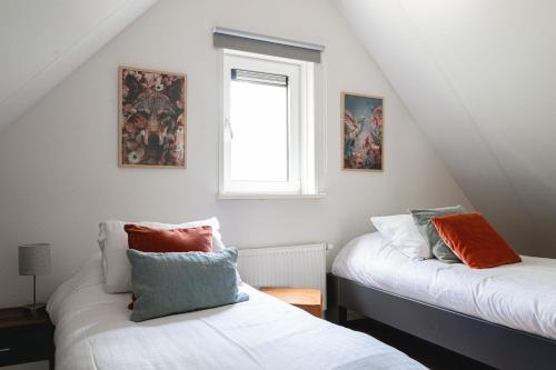 a attic room with two beds and a window at Luxe Vakantiehuis De Linde Veluwe in Nunspeet