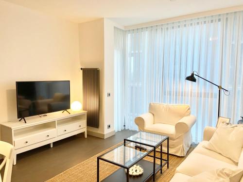 uma sala de estar com um sofá branco e uma televisão em Havuz olanağına sahip , otel konforu sunan daire em Istambul