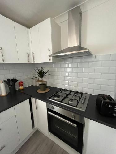 a kitchen with white cabinets and a stove top oven at Park View Homestay in Barking