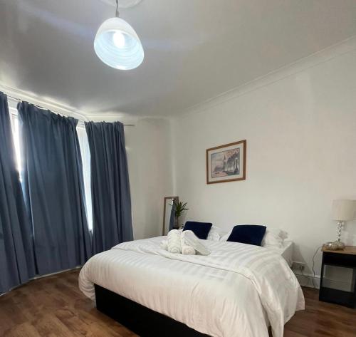 a bedroom with a large white bed with blue curtains at Park View Homestay in Barking