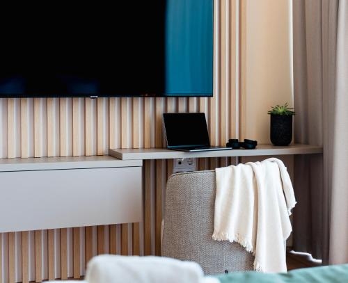 a room with a chair and a tv and a laptop at Zala Springs Golf Resort in Zalacsány