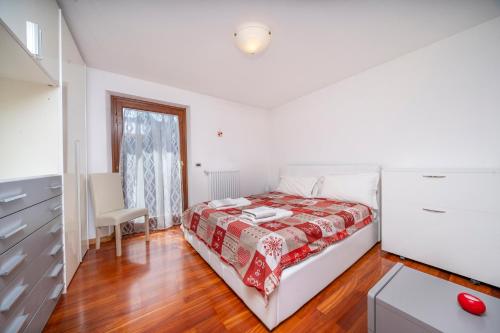 - une chambre blanche avec un lit et une commode dans l'établissement Le Coccinelle, à Tarvisio